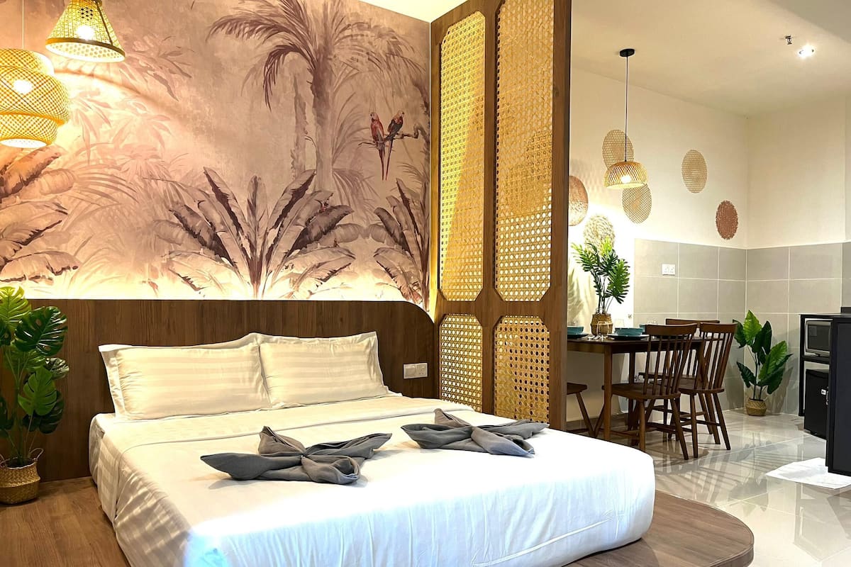 Una habitación de hotel moderna con una cama grande, un área de comedor y una pared decorativa con un mural tropical.