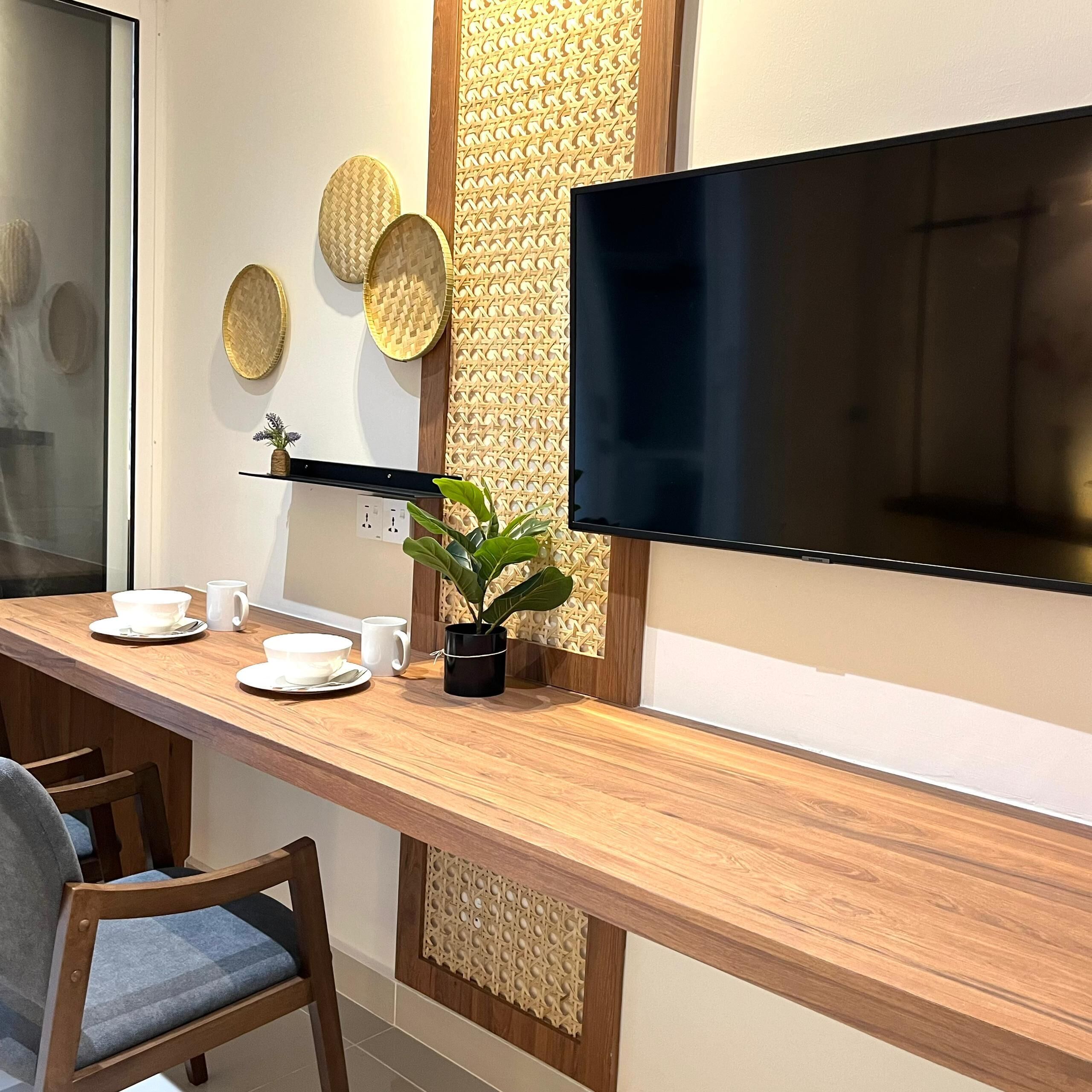A modern room with a wooden desk, a flat-screen TV, and decorative woven panels.