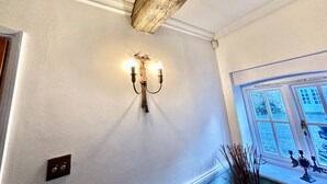 A hallway with a wall-mounted light fixture and a window with a view of a building.