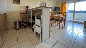 A compact kitchen with a dining area, a TV, and a view through the sliding glass door.