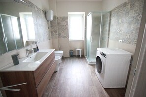 Un baño moderno con un lavamanos grande, inodoro y lavadora.