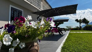 Un edificio con balcón, zona de estar al aire libre y una planta en maceta con flores.