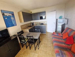 A compact living space with a dining area, kitchenette, and a sofa.