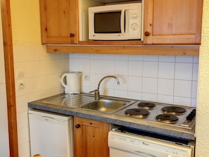 A compact kitchen with a microwave, sink, stove, and dishwasher.