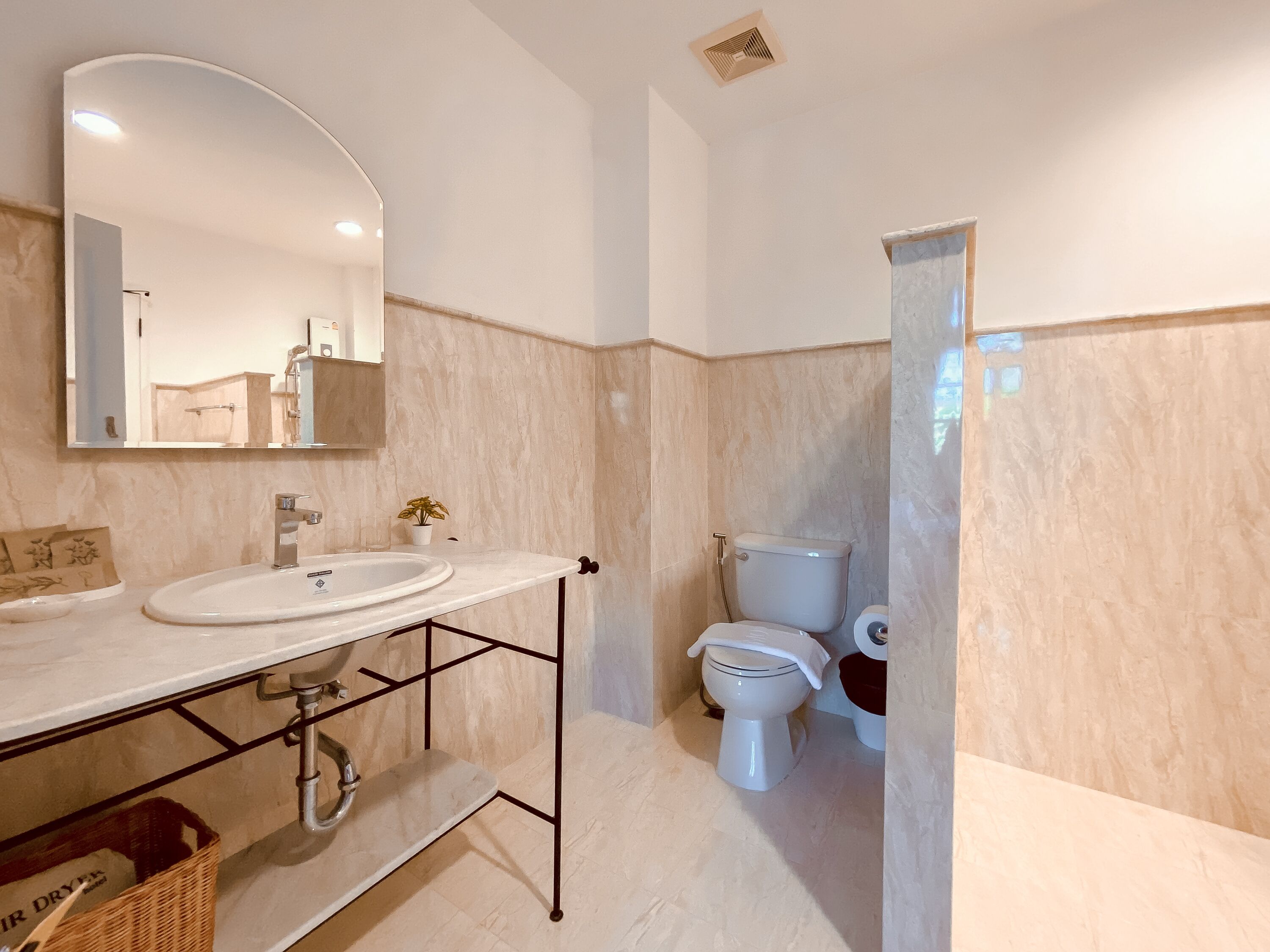 A bathroom with a double sink, a toilet, and a mirror.