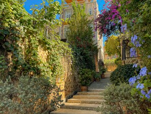 A stone staircase surrounded by lush greenery and flowering plants, leading up to a building with traditional architecture. - Villetta The Eyrie Khaoyai (Pak Chong)