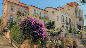 Un edificio de varios pisos con fachada de piedra, ventanas en arco y balcones.