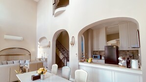 Una cocina moderna con armarios blancos, un refrigerador negro y una zona de comedor con mesa y sillas blancas.