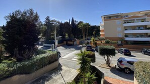 Un estacionamiento con autos, un paso de peatones y un edificio de varios pisos con balcones.