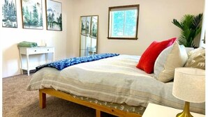 A bedroom with a bed, a desk, a chair, a lamp, and a window. - Orvis Outpost
 (Ridgway)
