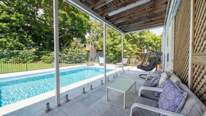 Ein überdachter Außenbereich mit Schwimmbad, Sitzgelegenheiten und einer Pergola.