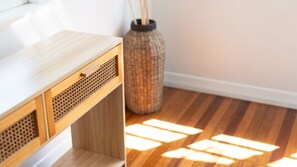 Ein Holztisch mit einer Schublade, einem gewebten Korb und einer Vase mit Zweigen.