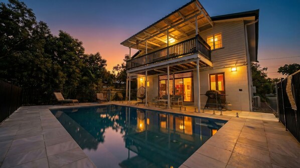 A two-story house with a swimming pool, outdoor seating, and a covered patio area.