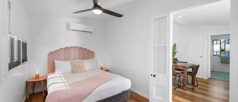 Una camera da letto con un letto, comodini, una ventola a soffitto e un condizionatore d'aria.