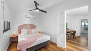 Un dormitorio con cama, mesitas de noche, ventilador de techo y aire acondicionado.