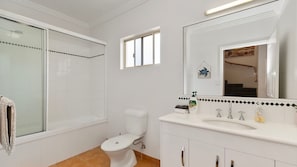 A bathroom with a toilet, a shower, a sink, and a mirror.