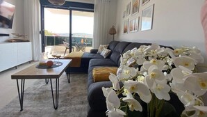 Un salon moderne avec un canapé foncé, une table basse et une grande fenêtre donnant sur l’extérieur.