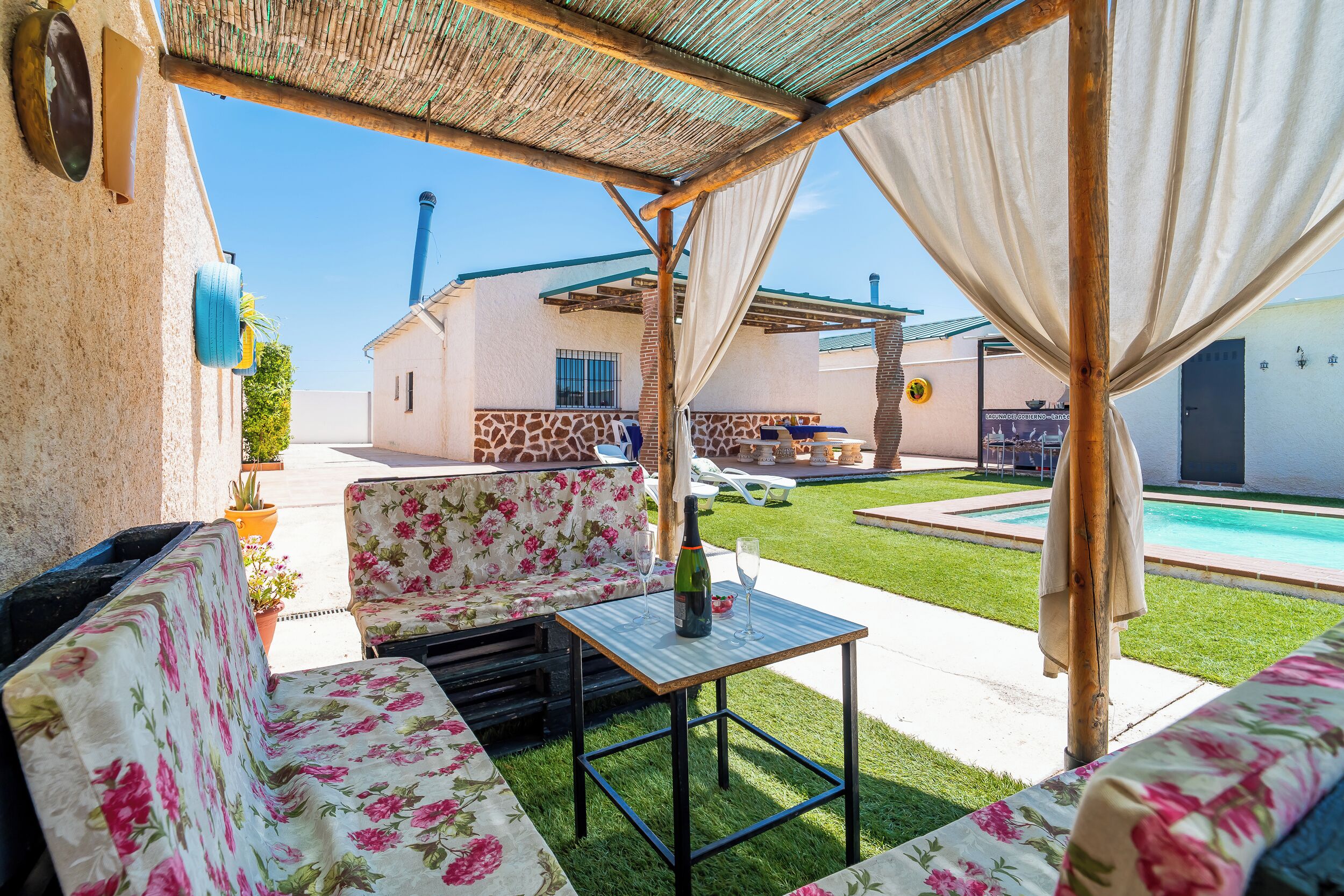 An outdoor patio with a sofa, table, and a pool in the background.