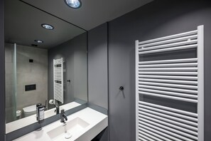 Un baño moderno con un espejo grande, un lavabo blanco y un perchero para toallas.