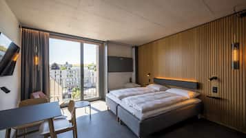 Een moderne hotelkamer met een groot bed, een bureau en uitzicht op de stad.