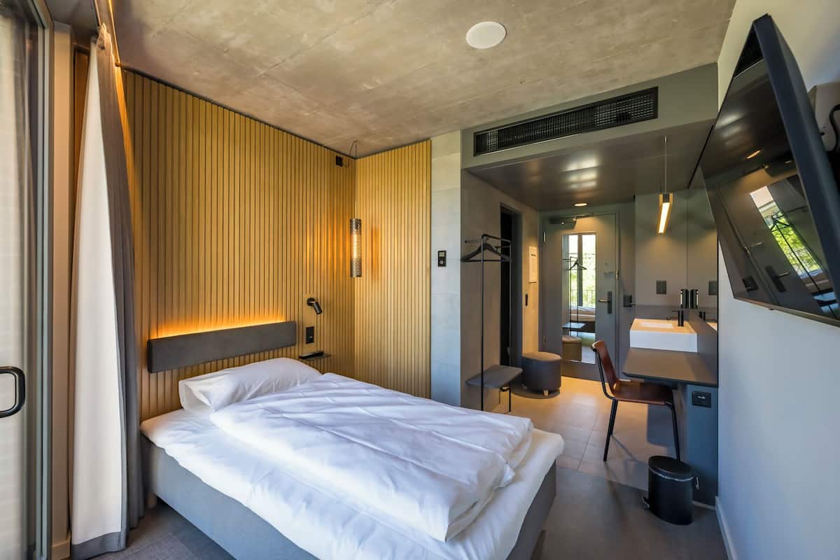 Una habitación de hotel moderna con cama, escritorio, silla y baño.