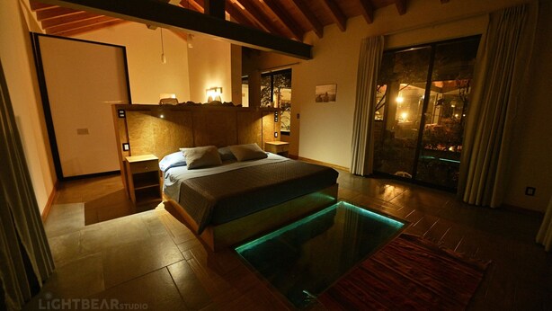 A bedroom with a bed, bedside table, and a view of the outside.