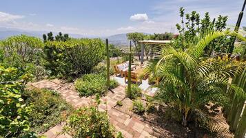 Un jardin agrémenté d’une pergola, d’un espace détente et offrant une vue sur les montagnes lointaines.
