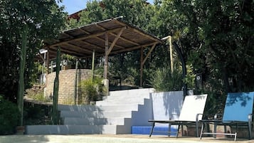 Une piscine dotée d’un espace de repos couvert et d’un escalier menant à la piscine.