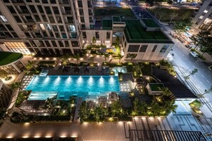 A rooftop swimming pool with lounge chairs and greenery, surrounded by modern buildings.