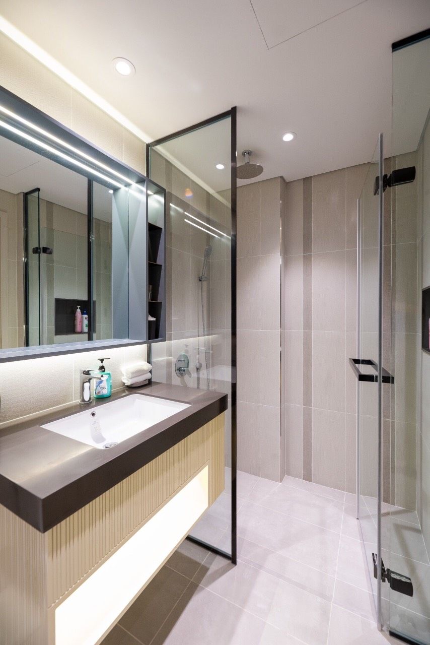 Une salle de bain moderne avec un grand miroir, un lavabo et une douche à parois de verre.