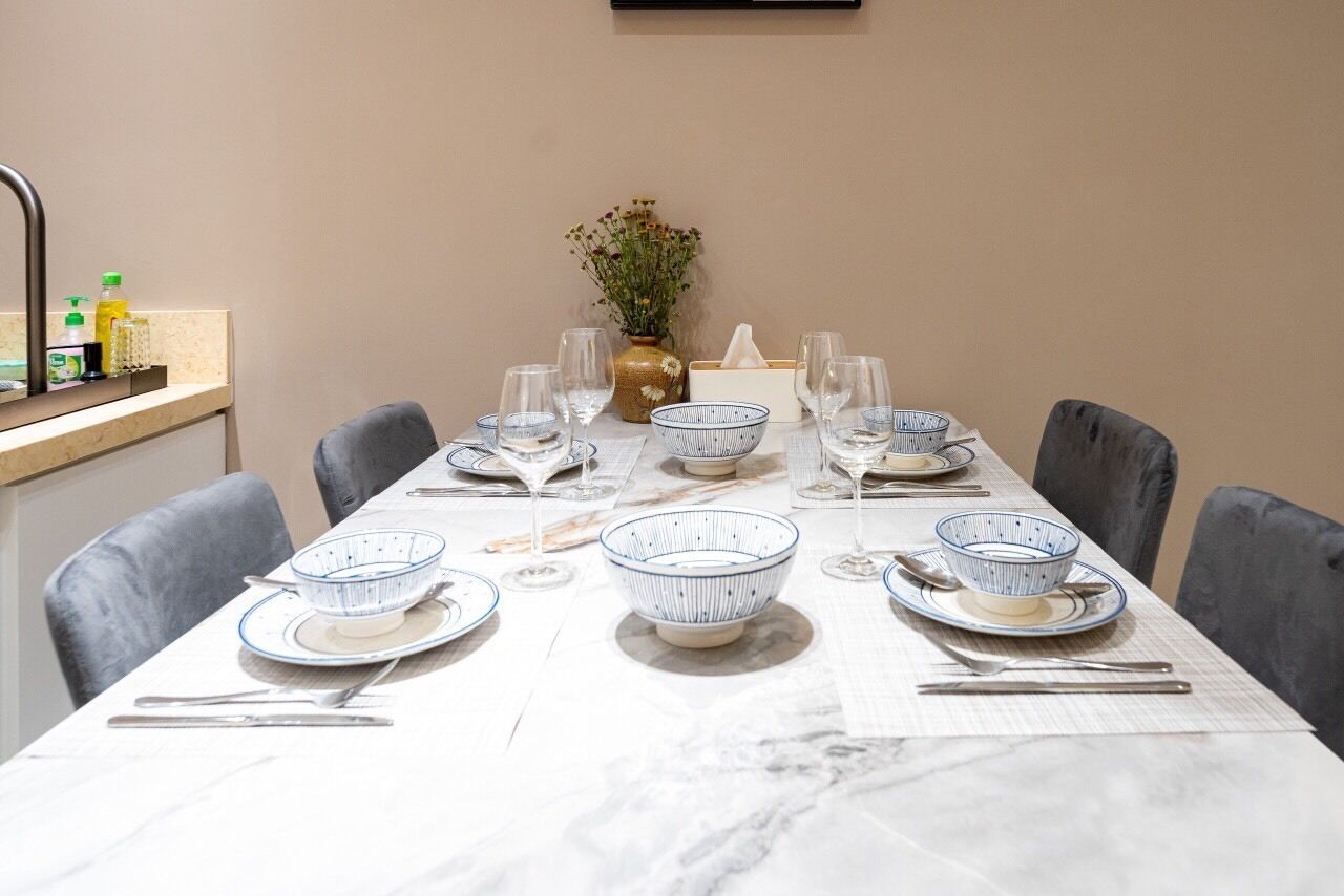 A dining table set with white plates, blue and white patterned bowls, and clear wine glasses.