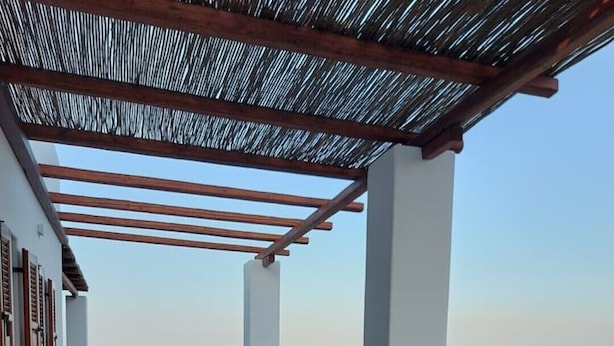 Eine Terrasse mit einem Holztisch, Stühlen und einem Blumentopf.