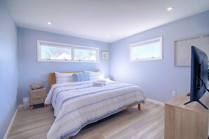 A bedroom with a bed, bedside tables, a television, and windows. - Water Views, Access to Grand Cove! (Dennis)