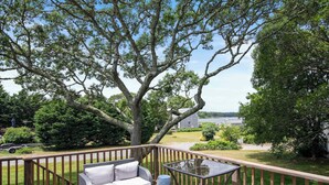 A deck with outdoor furniture, a glass table, and a view of a lake and house. - Water Views, Access to Grand Cove! (Dennis)