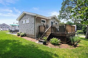 A two-story house with a deck, a small front yard, and a visible staircase. - Water Views, Access to Grand Cove! (Dennis)
