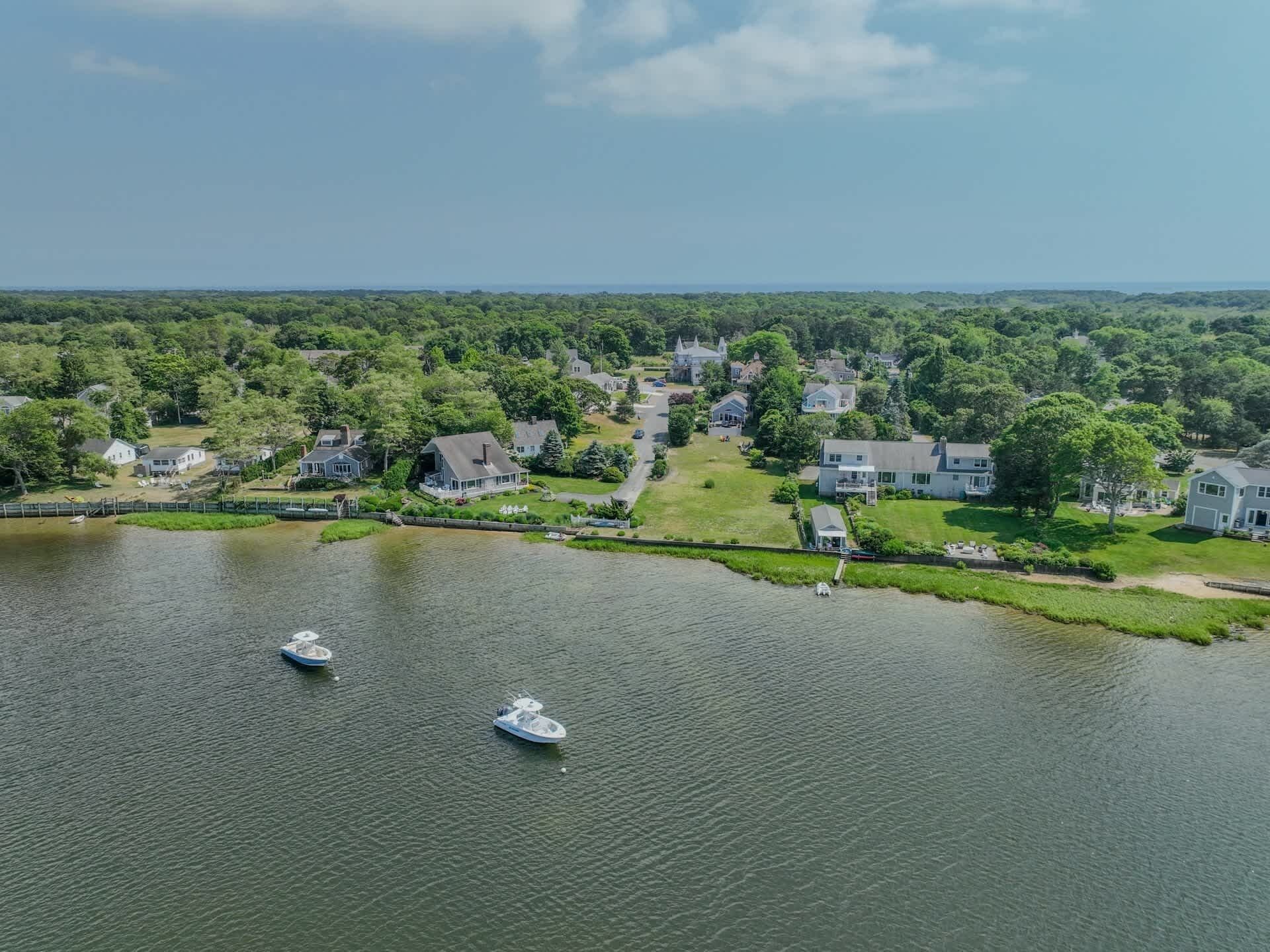 An aerial view of a lakeside residential area with houses, boats, and a dock.