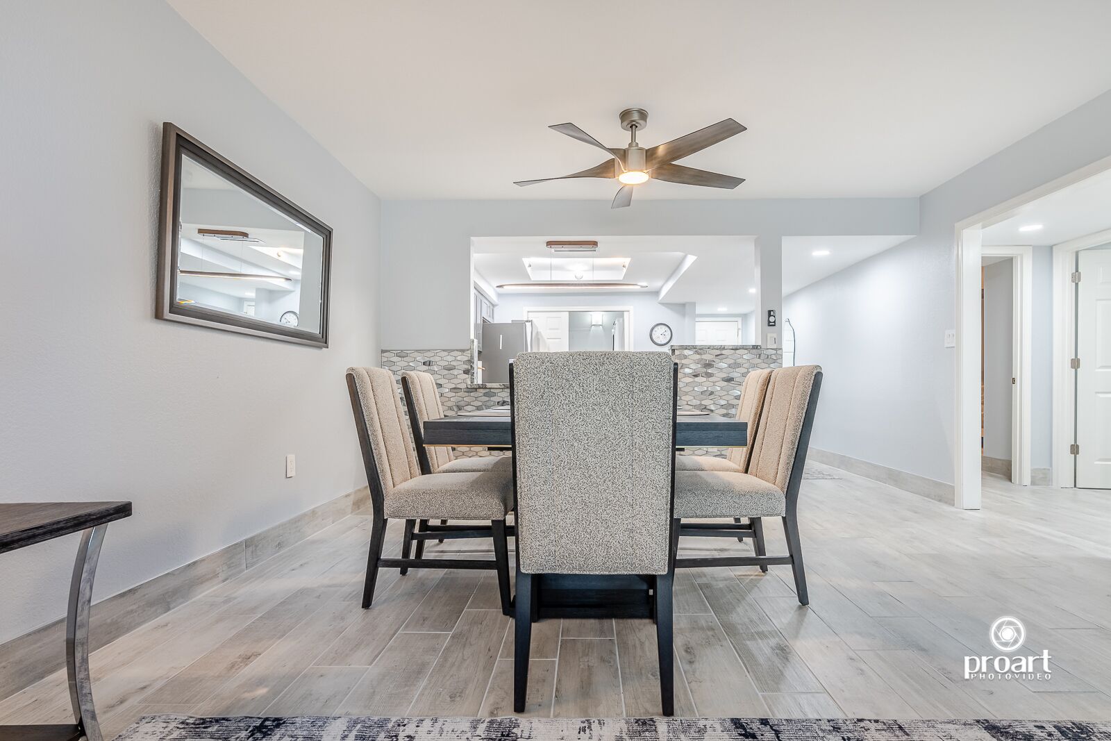 A dining area with a table and chairs, a ceiling fan, and a patterned rug.