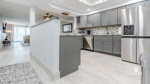 A modern kitchen with grey cabinets, stainless steel appliances, and a central island.