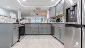 A modern kitchen with grey cabinetry, stainless steel appliances, and a central island.