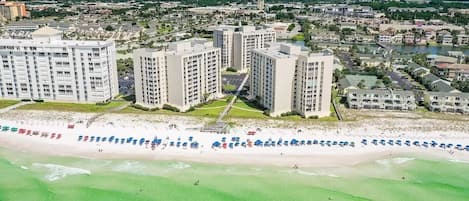 A coastal area with high-rise buildings, a beach with umbrellas, and a clear view of the ocean.