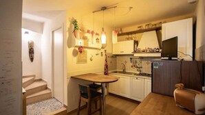 A compact kitchen with a wooden table and bar stools, white cabinets, and a built-in oven. - Single-family home (Scandicci)