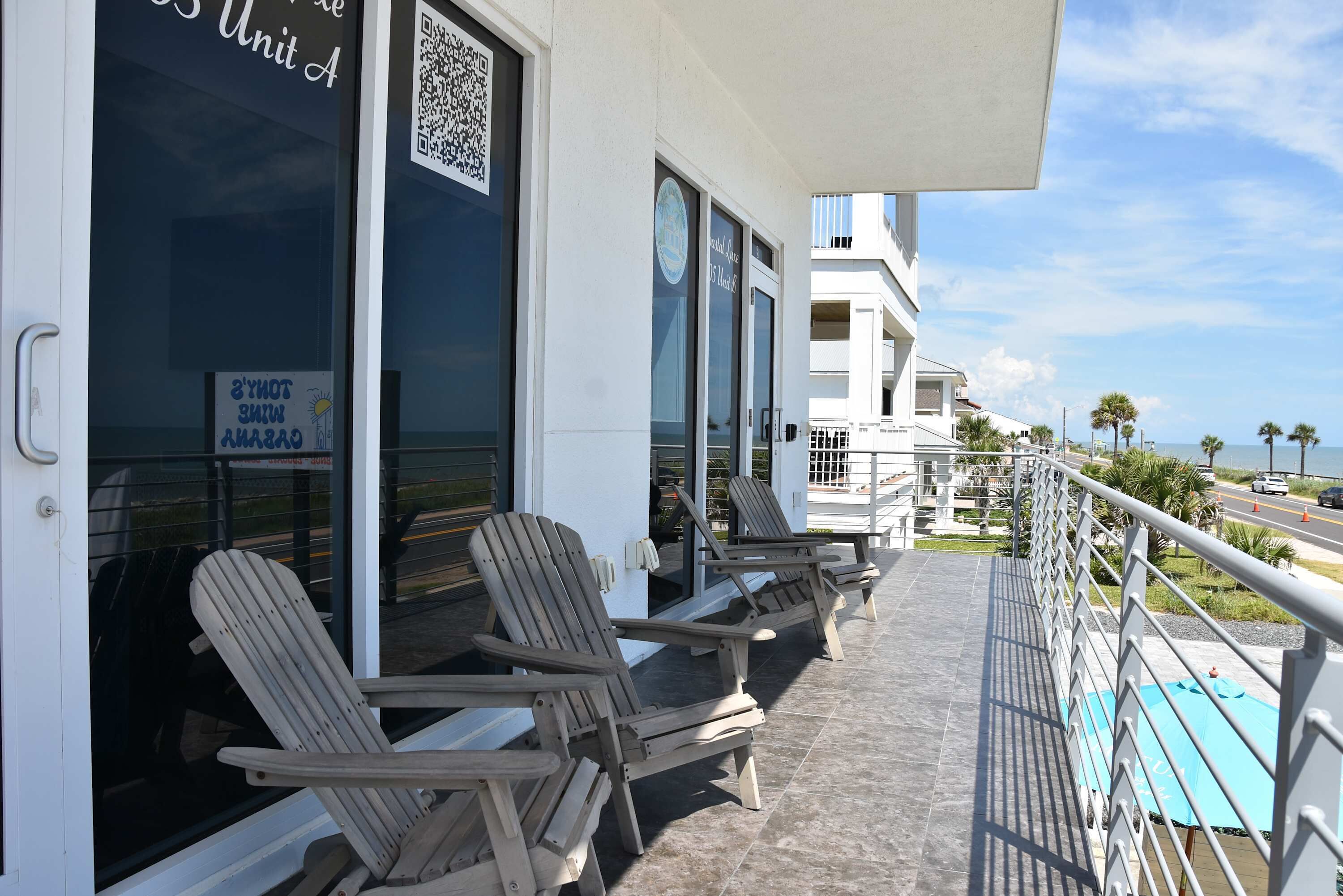 A balcony with lounge chairs, a QR code, and a sign indicating a 2-hour check-in policy.