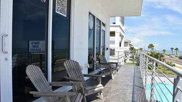 A balcony with lounge chairs, a QR code, and a sign indicating a 2-hour check-in policy.