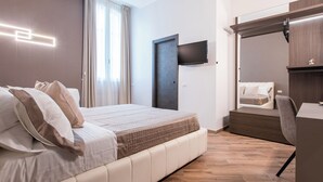 A modern hotel room with a bed, a TV mounted on the wall, a mirror above the bed, and a wooden floor. - The Dream Suites (Milan)