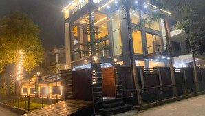A modern building with a glass facade, a wooden deck, and a gated entrance. - The Grand Mansion Hotel (Greater Noida)