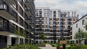Un moderno edificio de apartamentos con varios balcones, un patio central y un letrero que dice "RE".
