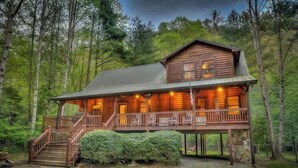 A log cabin with a porch, a staircase, and a stone foundation. - Hemptown Hideway (Mineral Bluff)