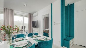 Un comedor moderno con una mesa de vidrio, sillas tapizadas en color turquesa y vistas al exterior.