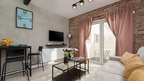 Una sala de estar moderna con sofá, mesa de centro, televisor y comedor con sillas y mesa.