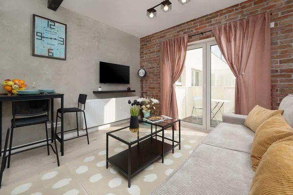 A stylish living room with a gray sofa, a black coffee table, and soft pink curtains, creating a cozy and elegant atmosphere.